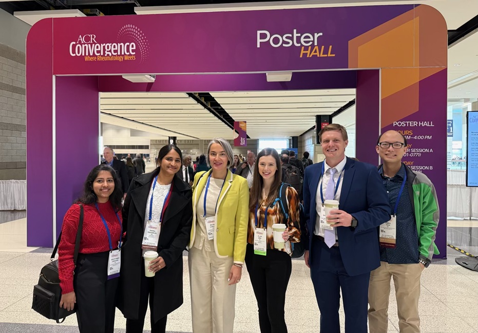 Six conference attendees wearing name badges stand together beneath a large purple entrance structure labeled “ACR Convergence” and “Poster Hall.” The group poses in a convention center hallway, with other attendees and poster hall signage visible in the background.