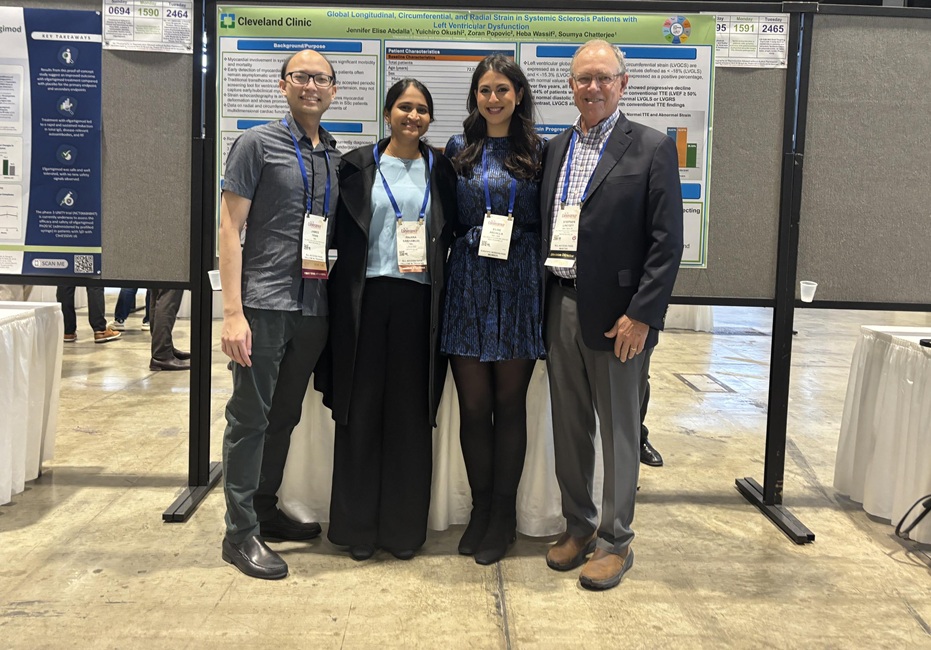 Four conference attendees wearing name badges stand together in front of a scientific research poster at a medical conference poster session.