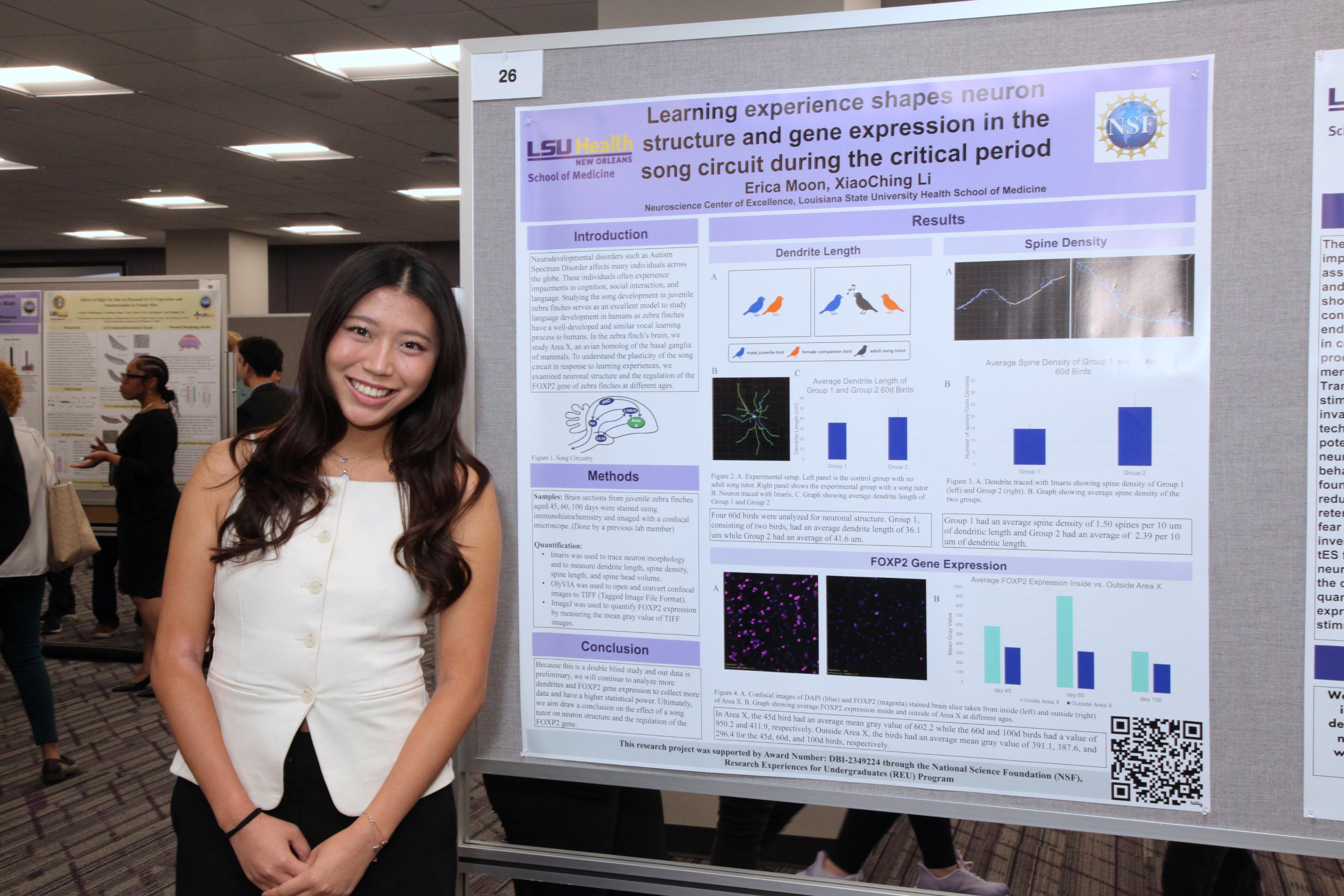 summer intern stands by her research poster