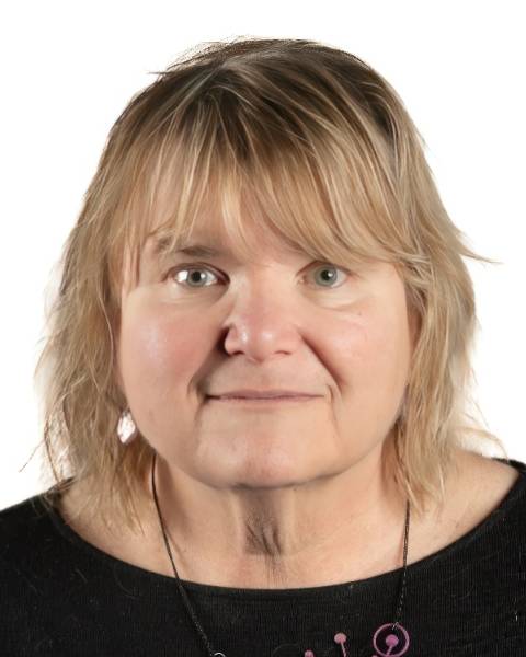 Professional headshot of a person with shoulder-length light hair wearing a black top, posed against a white background.