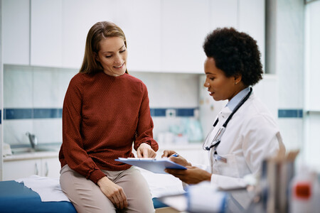 Female doctor discussing medical information with a female patient in an examination room