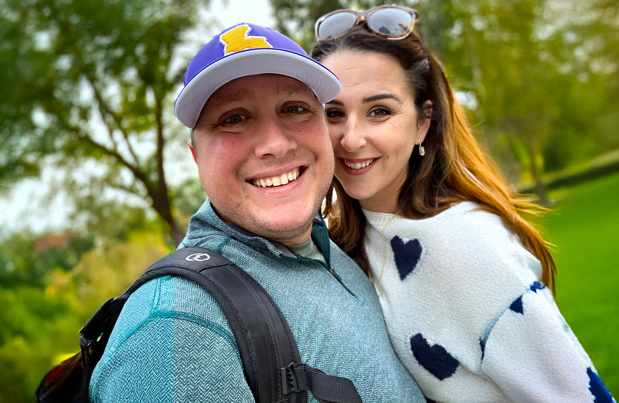 Brian, a lymphoma survivor and advocate for improved cancer care in Louisiana, smiles alongside his wife in a beautiful outdoor setting.