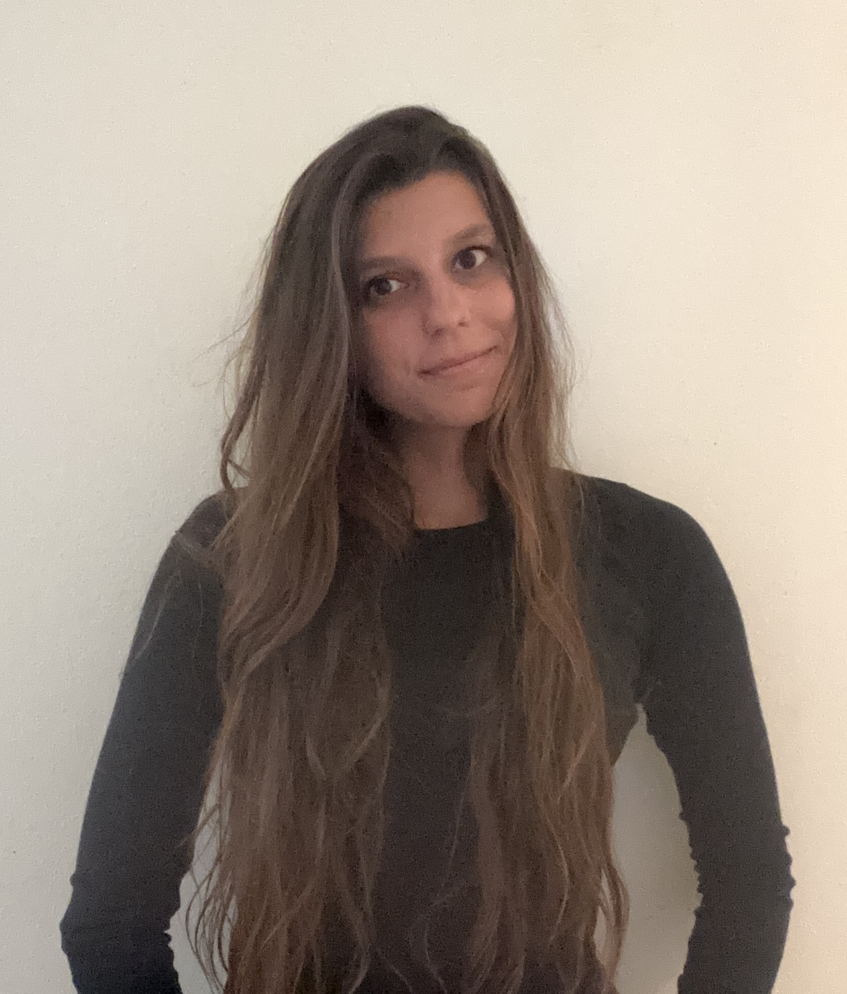 Lija Hoffman - The subject is dressed in professional attire with a relaxed posture and natural expression, photographed against a neutral background with soft lighting